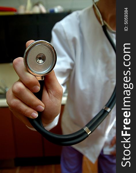 A stethoscope being held up to the camera lens being held by a female doctor in white lab coat. A stethoscope being held up to the camera lens being held by a female doctor in white lab coat.