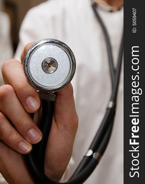 A stethoscope being held up to the camera lens being held by a female doctor in white lab coat. A stethoscope being held up to the camera lens being held by a female doctor in white lab coat.