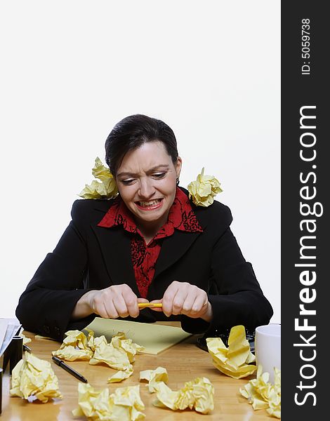 Woman in a business suit balancing a pencil under her nose surrounded by crumpled up pieces of yellow paper. Isolated against a white background. Woman in a business suit balancing a pencil under her nose surrounded by crumpled up pieces of yellow paper. Isolated against a white background