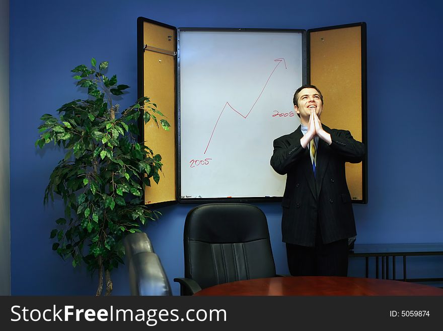 Businessman in a conference room with his hands joined praying for success. Businessman in a conference room with his hands joined praying for success