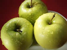 Green Apple On Red And Water Drops Stock Images
