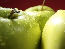 Green Apple On Red With Water Drops Royalty Free Stock Image