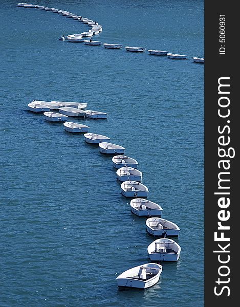 Small white boats forming an arc shape in a harbor in France. Small white boats forming an arc shape in a harbor in France