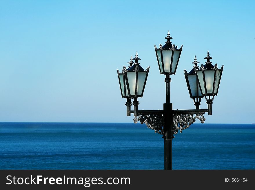 Lonely city lantern on a background of the sea and the sky