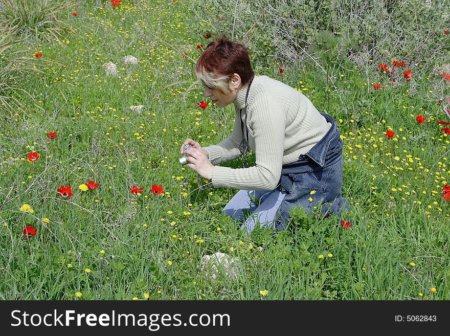The young woman - photographer photographes a flower
