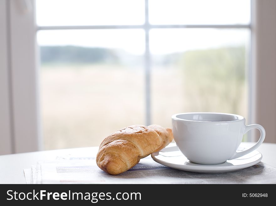 Cup of coffee and croissant on the newspaper / business break