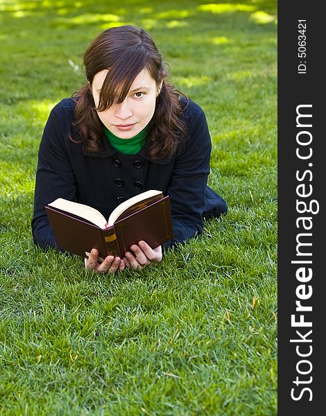 Beautiful brunette woman reading on the grass