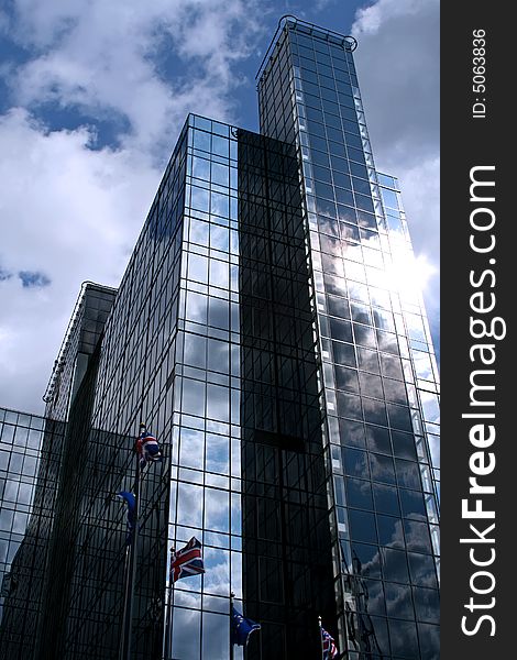 Modern blue glassed office building with flags outside