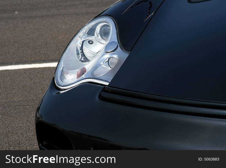Black supercar headlight with concrete background