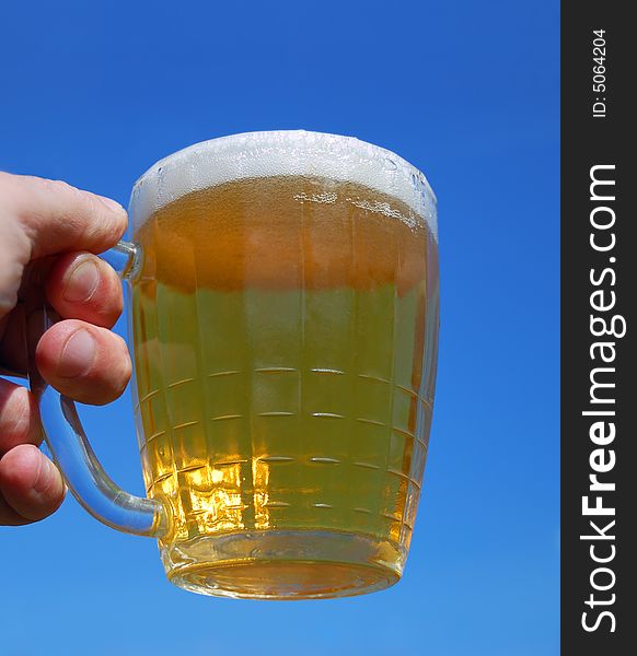 Hand with beer mug over a blue background