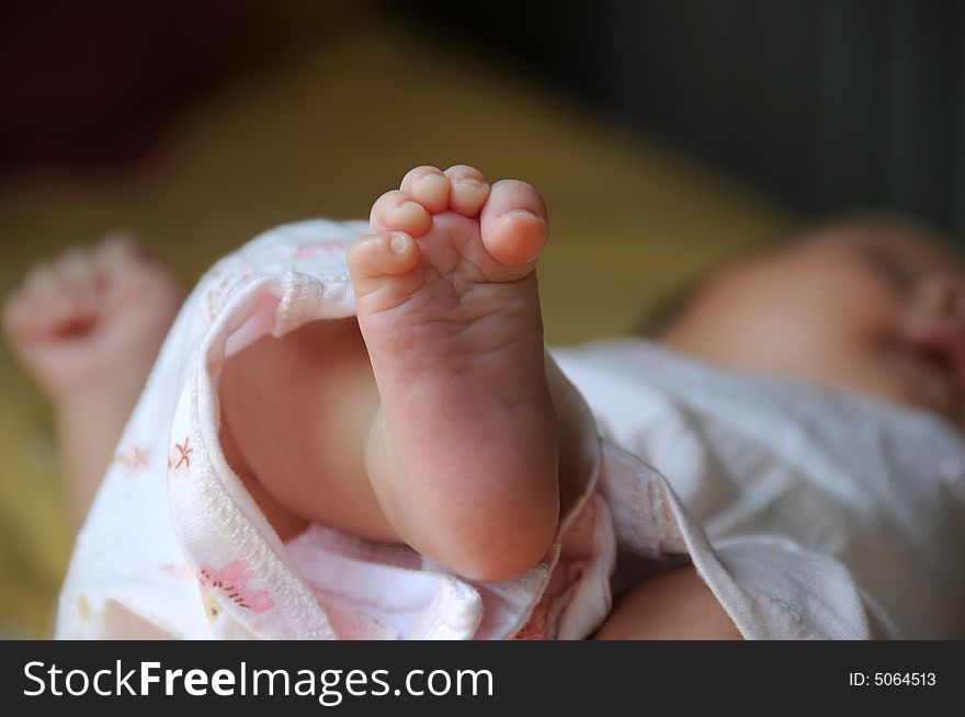 The bare foot with grasped fingers of a newborn baby. It's fleshly with the pink color. So lovely and cute. The bare foot with grasped fingers of a newborn baby. It's fleshly with the pink color. So lovely and cute.