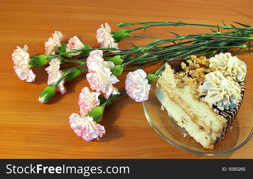 Bouquet of pink carnations and piece of a cake. Bouquet of pink carnations and piece of a cake