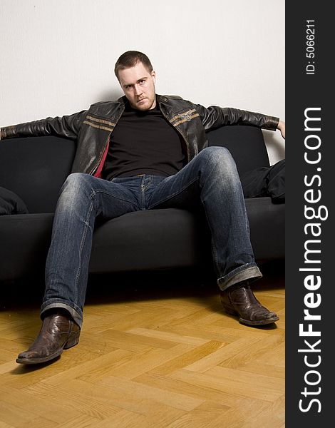 Young man sitting on a black sofa. Young man sitting on a black sofa