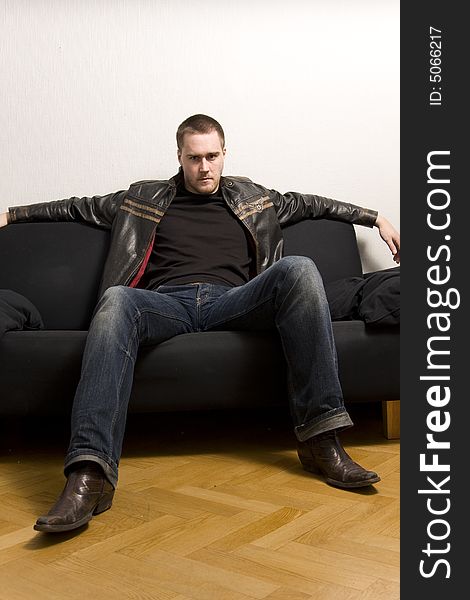 Young man sitting on a black sofa. Young man sitting on a black sofa