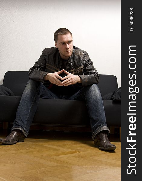 Young man sitting on a black sofa. Young man sitting on a black sofa