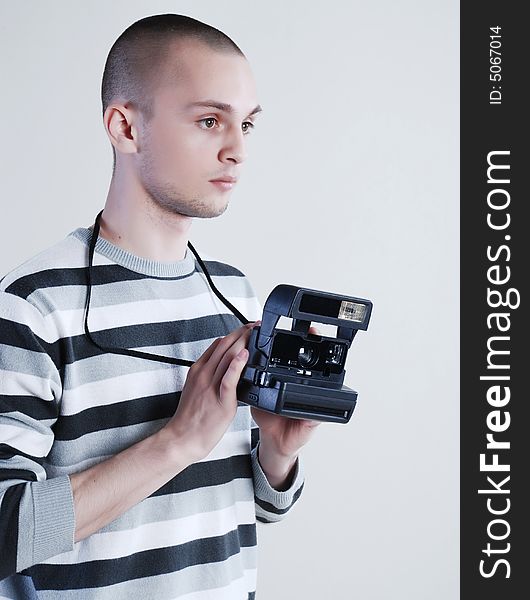 Young man photographer at white background with camera