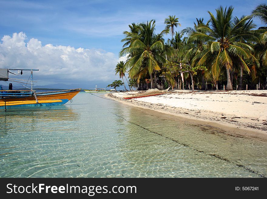 A beautiful white sand beach with palms and a colorful boat. A beautiful white sand beach with palms and a colorful boat