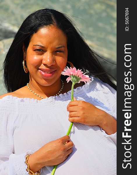 Young Black woman holding a pink flower