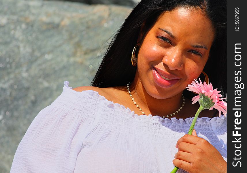 Black woman holding a pink daisy. Black woman holding a pink daisy