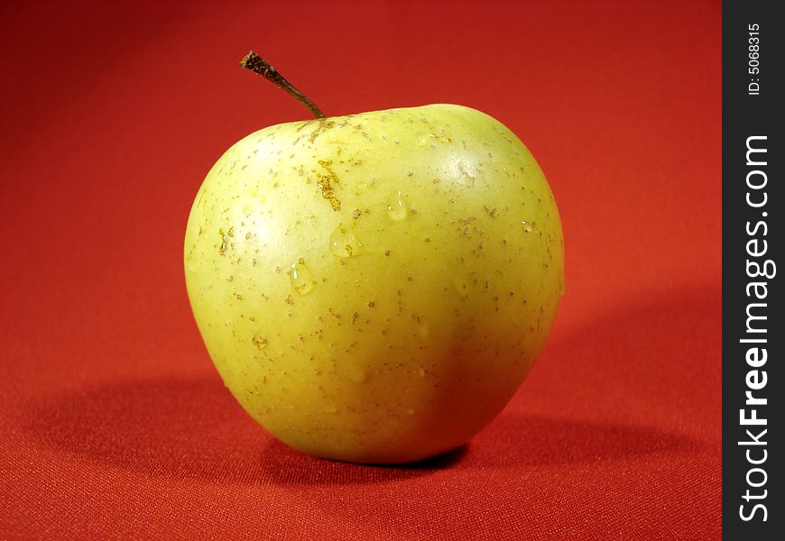 Green apple on red background closeup