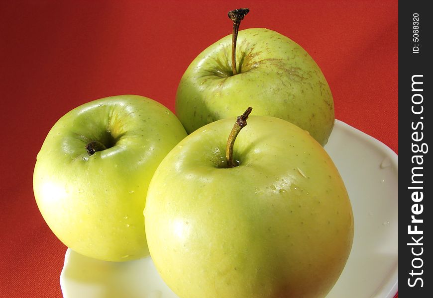 Three green apples on red