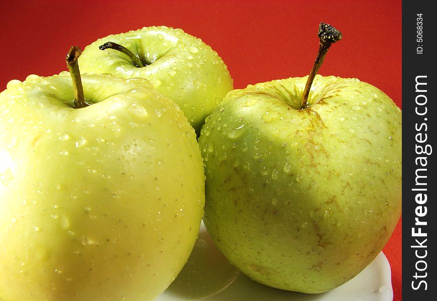 Fresh green apples closeup with water drops and red background. Fresh green apples closeup with water drops and red background