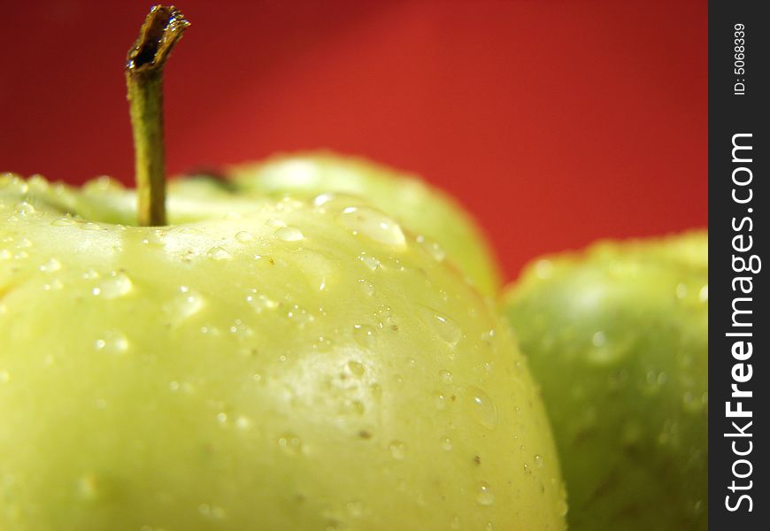 Green apple on red and waterdrops