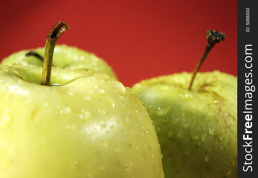 Fresh green apples closeup with water drops and red background. Fresh green apples closeup with water drops and red background