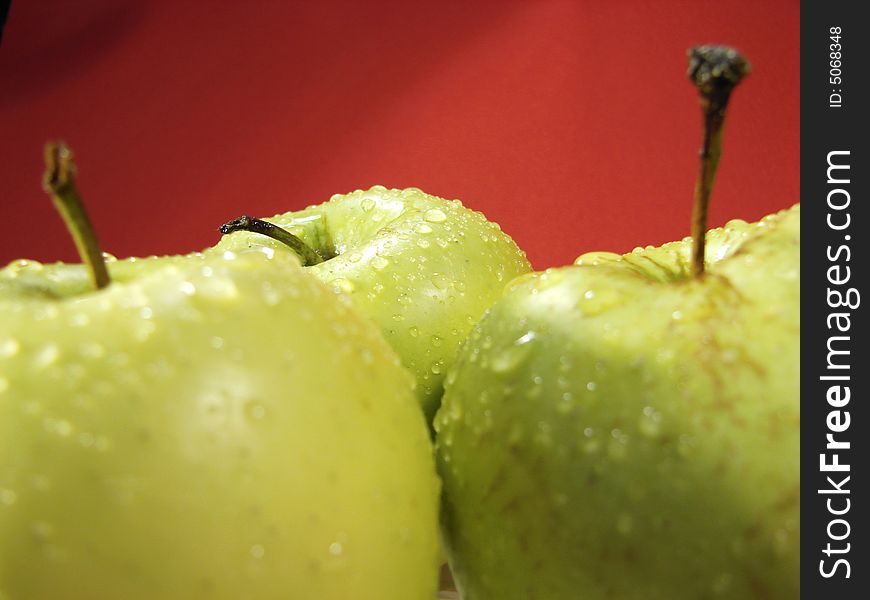 Fresh green apples closeup with water drops and red background. Fresh green apples closeup with water drops and red background