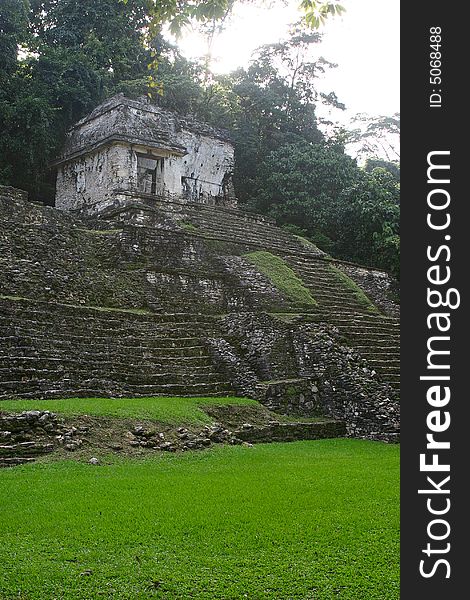 Antique ruins of mayan tomb over green grass