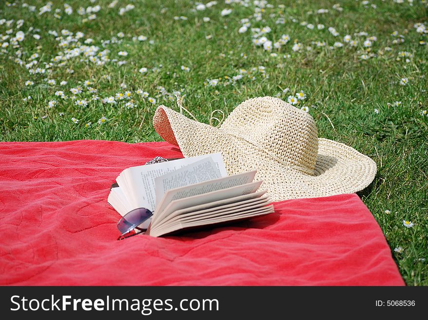 Hat,dook and sunglasses on a towel in a daisy filled meadow. Hat,dook and sunglasses on a towel in a daisy filled meadow