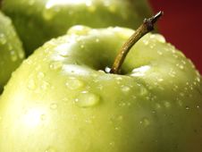 Green Apple On Red With Water Drops Stock Image