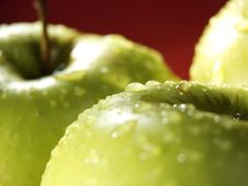 Green Apple On Red With Water Drops Royalty Free Stock Photos