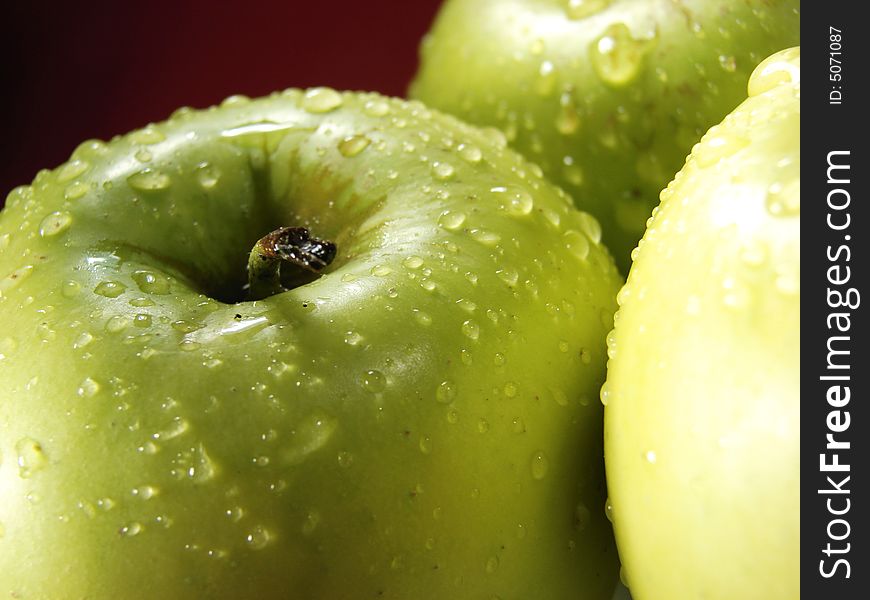 Fresh green apples closeup with water drops and red background. Fresh green apples closeup with water drops and red background