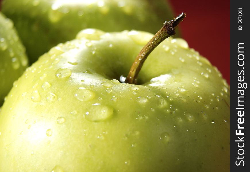 Fresh green apples closeup with water drops and red background. Fresh green apples closeup with water drops and red background