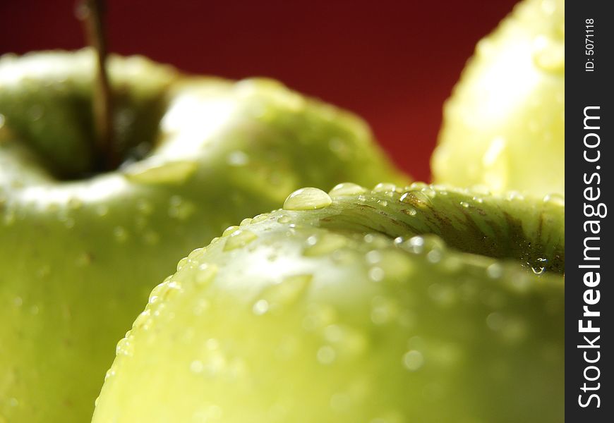 Fresh green apples closeup with water drops and red background. Fresh green apples closeup with water drops and red background