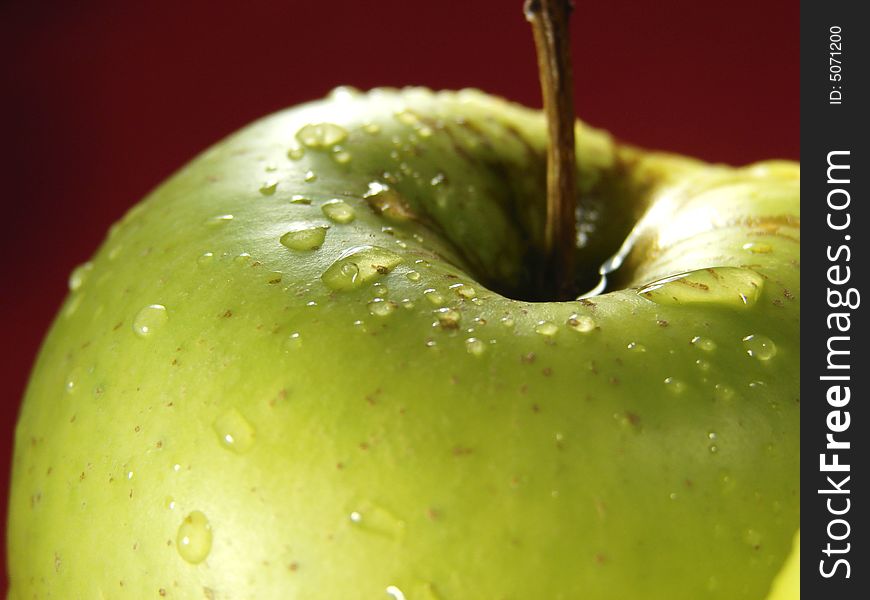 Green Apple On Red With Waterdrops