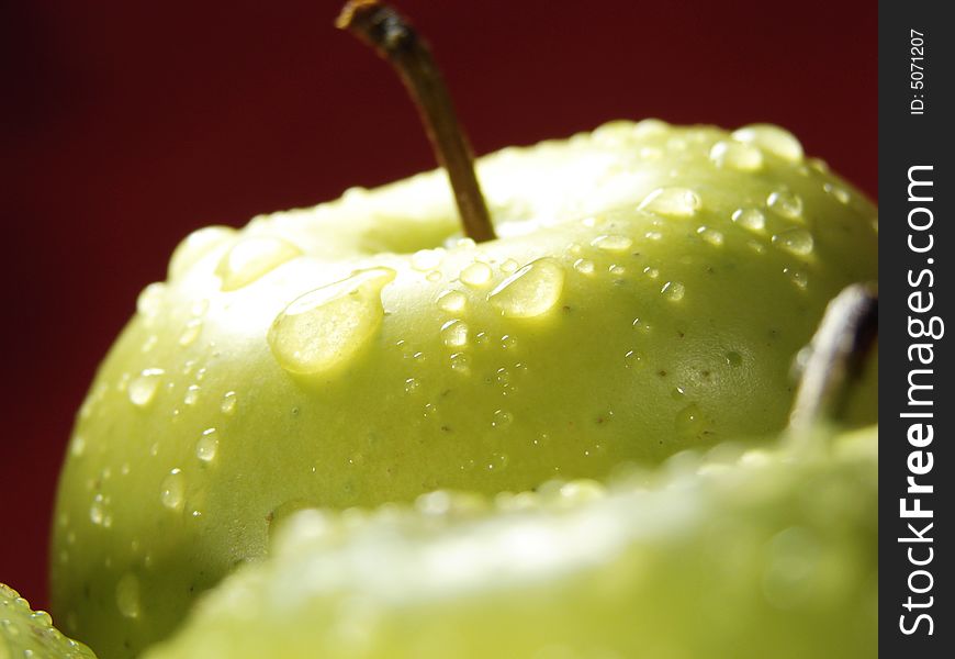 Fresh green apples closeup with water drops and red background. Fresh green apples closeup with water drops and red background