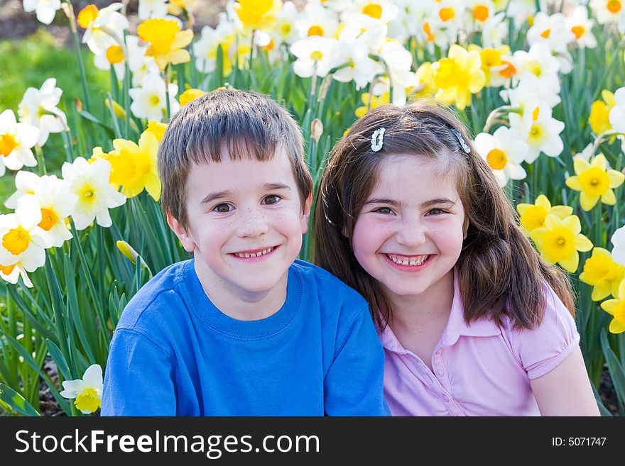 Two Little Friends Sitting in Front of Daffodils. Two Little Friends Sitting in Front of Daffodils