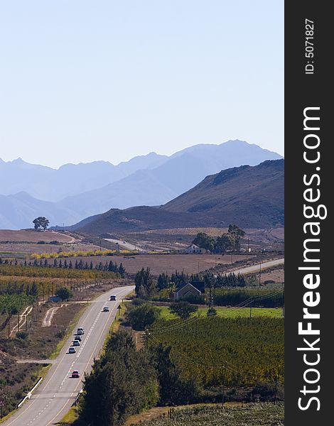 A country road through the mountains on a clear day with blue sky. A country road through the mountains on a clear day with blue sky