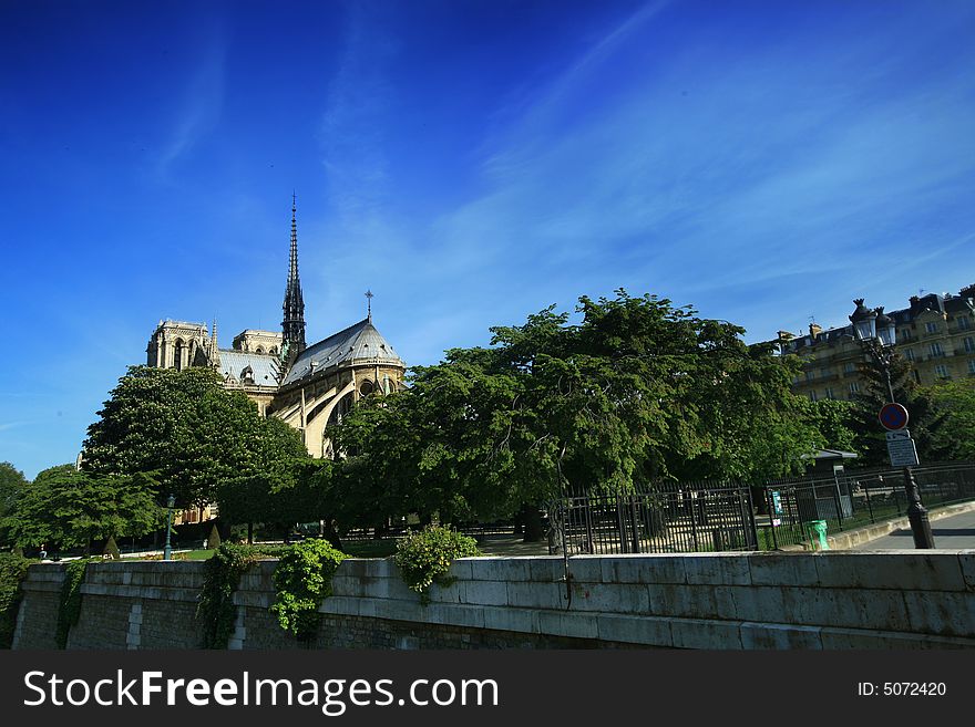 Notre Dame basilica in Paris, also known as Notre-Dame de Paris on spring blue sky and grenn trees.