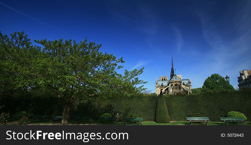 Panoramic view Notre Dame basilica in Paris, also known as Notre-Dame de Paris on spring blue sky and grenn trees.