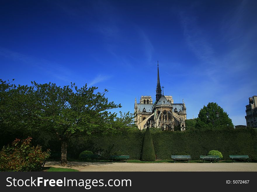 Notre Dame basilica in Paris, also known as Notre-Dame de Paris on spring blue sky and grenn trees.