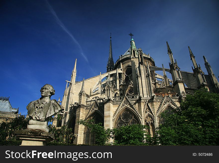 Notre Dame basilica in Paris, also known as Notre-Dame de Paris on spring blue sky and grenn trees.