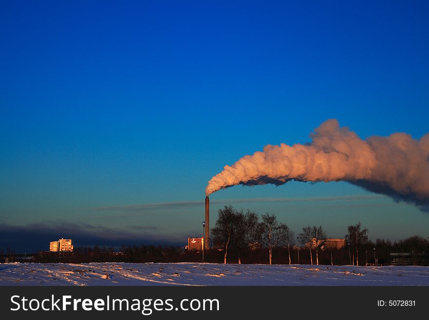 Factory smoke on blue sky in winter sunset