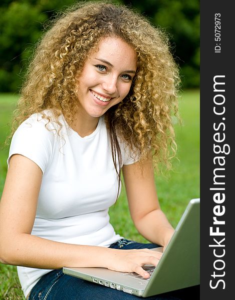 A beautiful young woman using a portable computer outside. A beautiful young woman using a portable computer outside