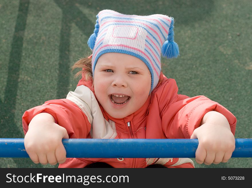 A little girl hanging on the horizontal bar at the playground. A little girl hanging on the horizontal bar at the playground