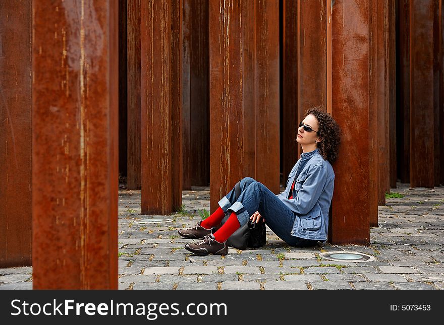 Woman waits between rusty colu