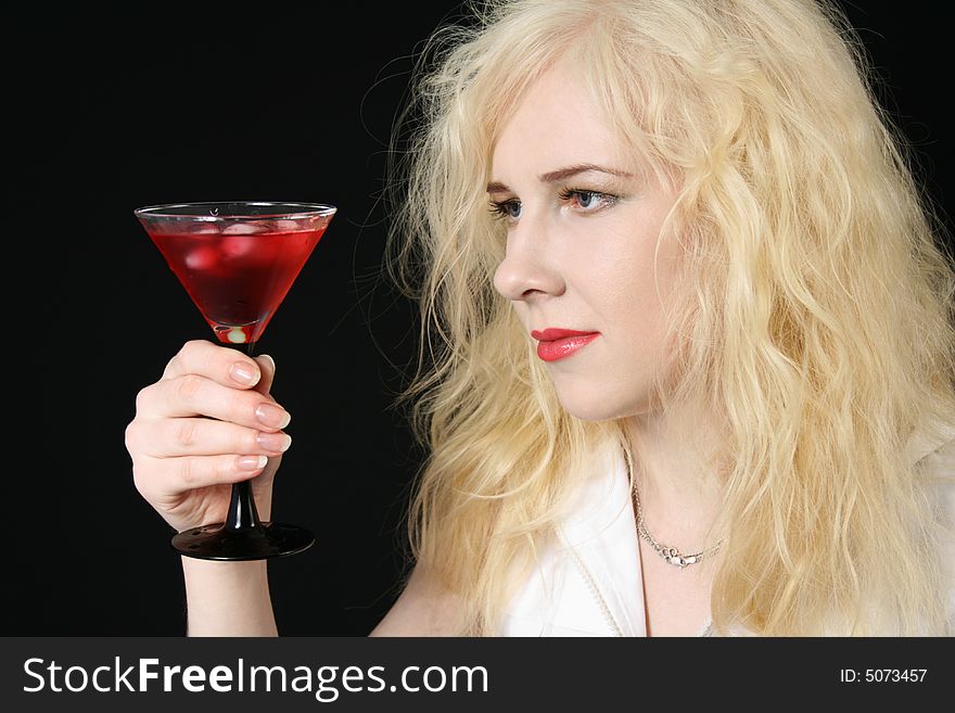 Young blond woman holds martini against the black background. Young blond woman holds martini against the black background