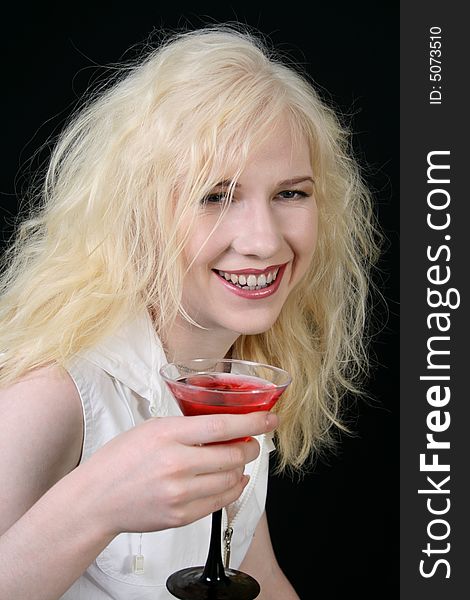 Young blond woman holds martini against the black background. Young blond woman holds martini against the black background